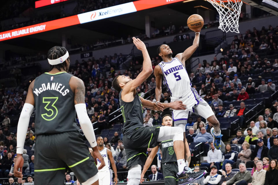 Sacramento Kings guard De'Aaron Fox (5) drives past Minnesota Timberwolves center Rudy Gobert for a basket as Timberwolves forward Jaden McDaniels (3) watches during the second half of an NBA basketball game Saturday, Jan. 28, 2023, in Minneapolis. The Timberwolves won 117-110. (AP Photo/Craig Lassig)