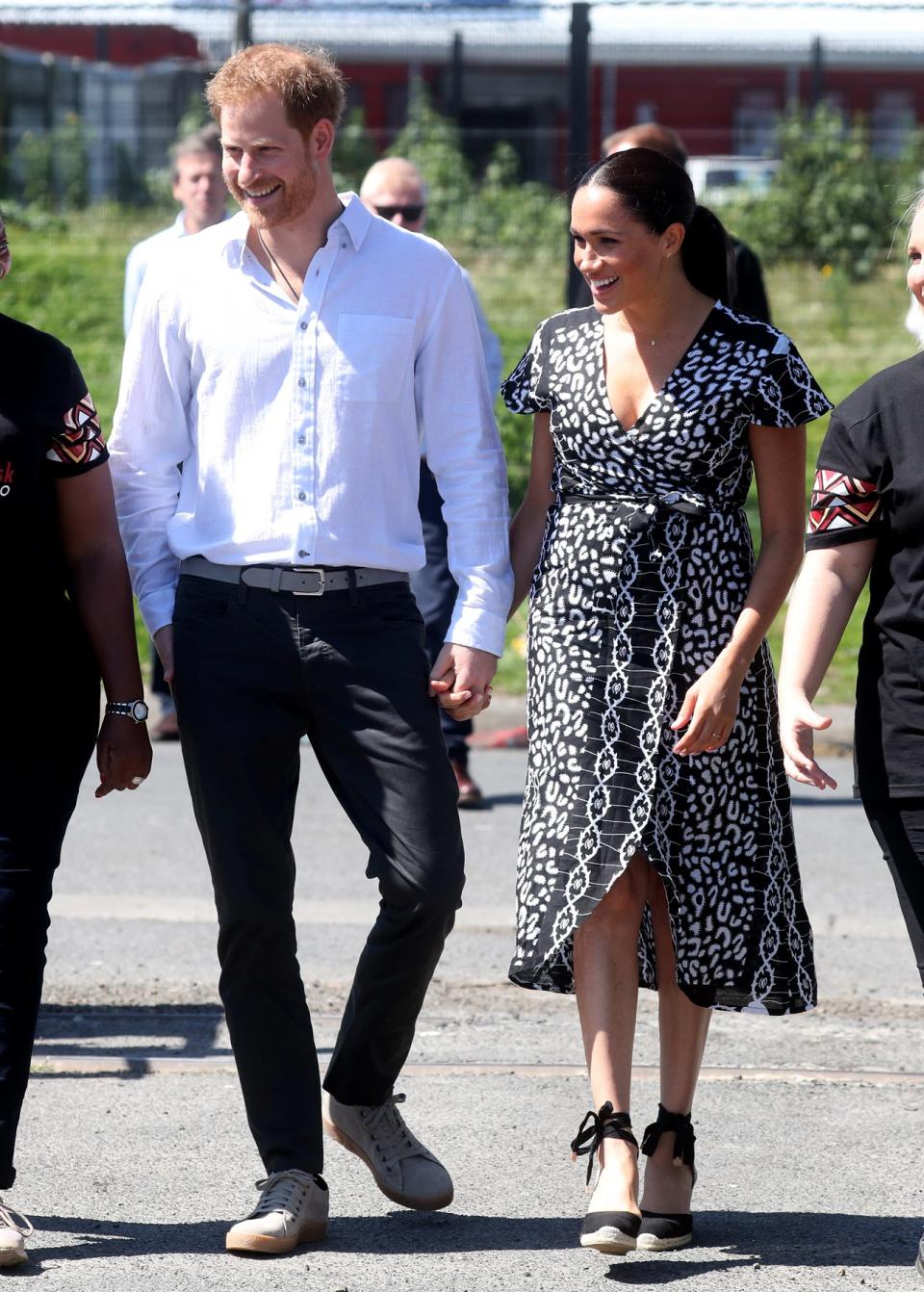 Prince Harry and Meghan Markle's royal tour (their first as a family of three!) is off to a PDA-filled start! The couple <a href="https://people.com/royals/meghan-markle-and-prince-harry-step-out-for-first-outing-on-tour-in-south-africa-holding-hands/" rel="nofollow noopener" target="_blank" data-ylk="slk:held hands during their visit;elm:context_link;itc:0;sec:content-canvas" class="link ">held hands during their visit</a> to Nyanga township, where they took a workshop run by an NGO called Justice Desk. 