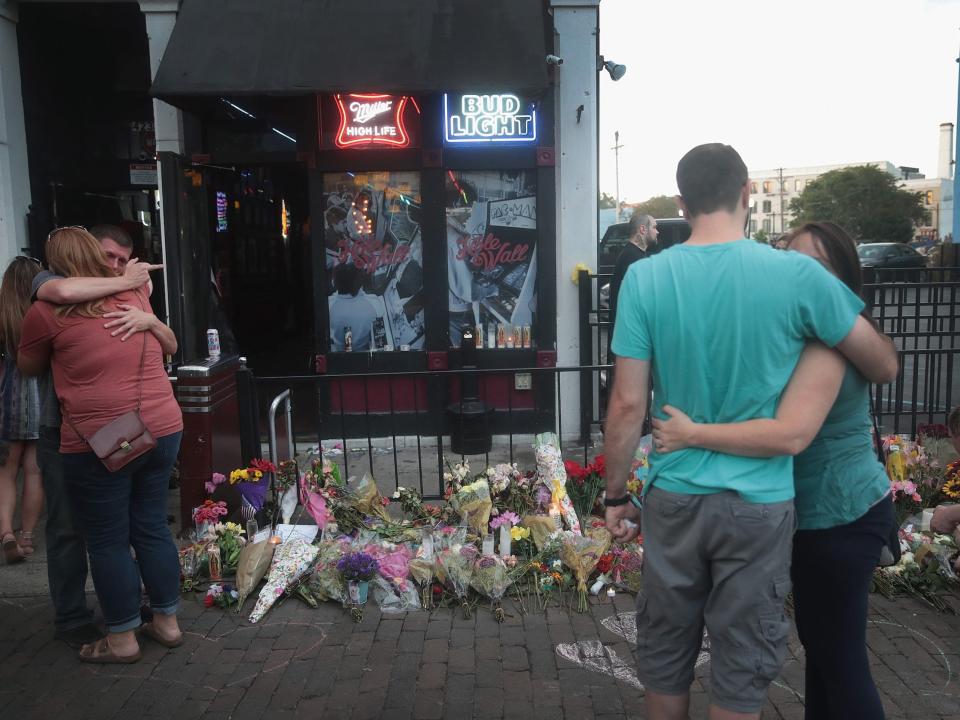 People embrace by a memorial for a mass shooting in Oregon in 2019