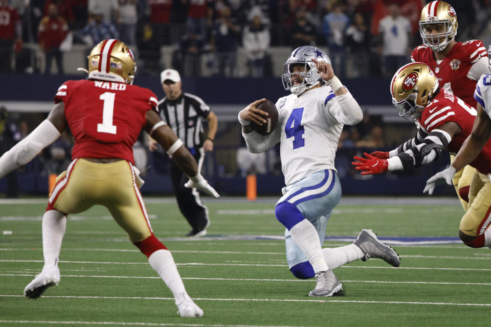 El quarterback de los Dallas Cowboys, Dak Prescott (4), empieza a deslizarse frente al safety de los San Francisco 49ers Jimmie Ward (1) después de correr con segundos restando en el juego de comodines de la NFL en Arlington, Texas, domingo 16 de enero de 2022. (AP Foto/Ron Jenkins)