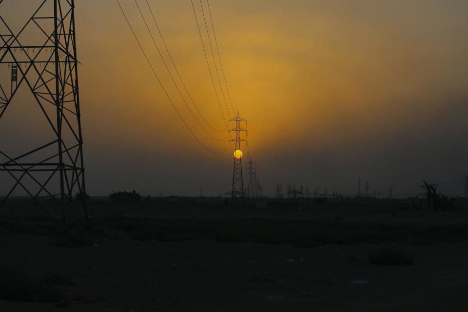 The sun sets behind the transmission lines of electric power from Iran to Iraq in Basra, Iraq, Tuesday, July 29, 2021. In Iraq, electricity is a potent symbol of endemic corruption, rooted in the country’s sectarian power-sharing system. This contributes to chronic electrical outages of up to 14 hours a day in a major oil-producing nation with plentiful energy resources. (AP Photo/Nabil al-Jurani)