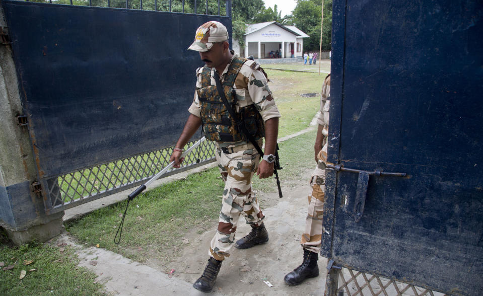 In this Aug. 31, 2019 photo, security men guard as people check their names in the final list of National Register of Citizens in Morigaon district, Assam, India. About 1.9 million people were left out of the National Register of Citizens _ a mammoth exercise to weed out illegal mainly Bangladeshi immigrants from Assam’s more than 32 million people. (AP Photo/Anupam Nath)