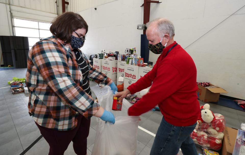 Molly White, left, and CEO Ed Wnorowski fill a bag with donations during the Santa Shop inside St. Vincent de Paul's Family Success Center in Louisville, Ky. on Dec. 13, 2020.  The program provided customers with toys and games donated by Toys for Tots and gift cards.