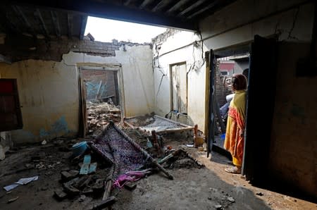 A woman stands at the entrance of a room after its roof was collapsed in an earthquake in Jatlan, Mirpur