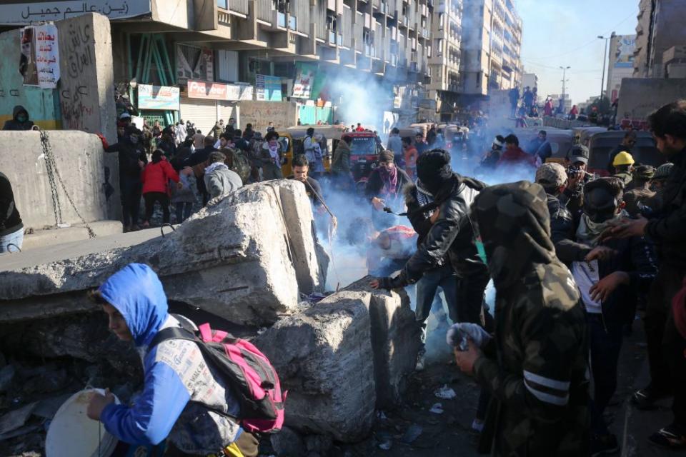 Iraqi protesters duck to avoid tear gas canisters amid clashes with security forces during an anti-government demonstration in Al-Khilani square in the capital Baghdad, on January 26, 2020. Source: Getty