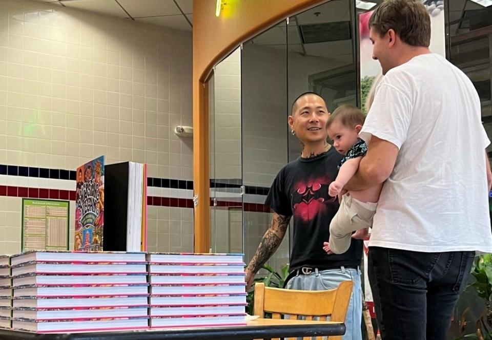 Danny Bowien poses for a picture with a fan during a book-signing at Lee's Sandwiches in Oklahoma City