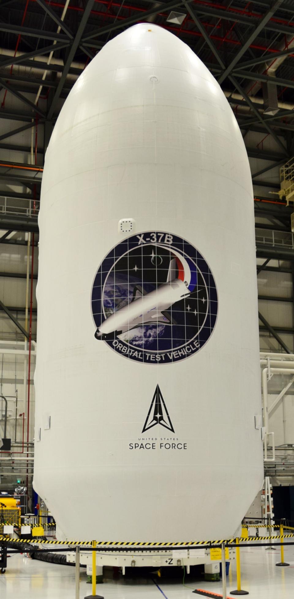 an egg-shaped rocket payload fairing in a hangar with the words 