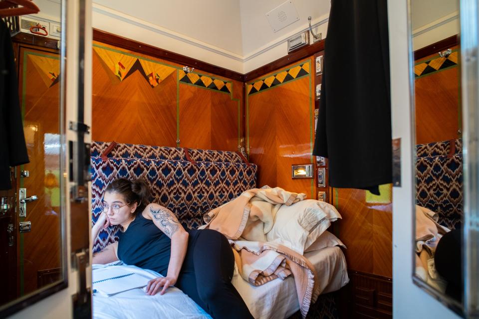 The author looks on while laying in a train bunk in a historic cabin with wood finishings