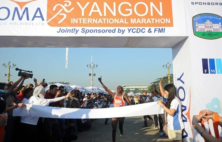 Kenya's Gitau Kariuki, 25, celebrates as he crosses the finish line to win Myanmar's first international marathon in decades, in Yangon, on January 27, 2013. Hundreds of runners streamed through Yangon on Sunday for Myanmar's first international marathon in decades, in another sign of the dramatic changes sweeping the former army-ruled country