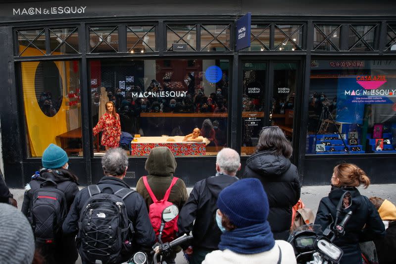 French actors perform a play behind store window in Paris