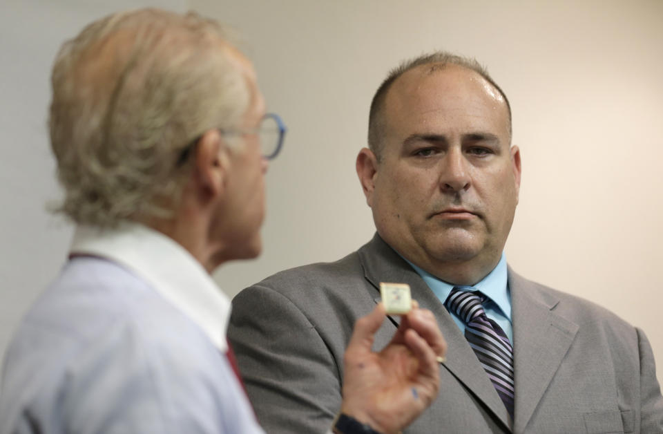 Attorney Jeff Anderson, left, holds up a physical fitness badge used by the Boy Scouts of America as Richard Halvorson looks on during a news conference in Newark, N.J., Tuesday, April 30, 2019. Halvorson is alleging sexual abuse in a lawsuit filed against the Boy Scouts of America. The abuse occurred under the guise of trying to earn the fitness badge when Halvorson was an 11-year-old boy scout. (AP Photo/Seth Wenig)