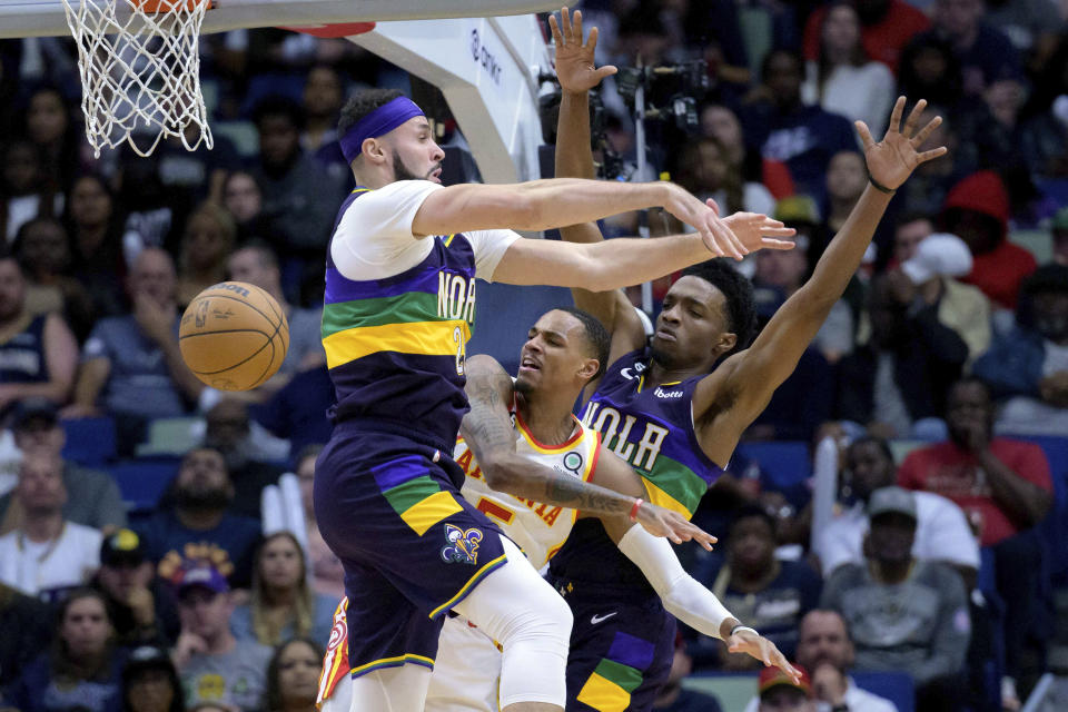 Atlanta Hawks guard Dejounte Murray (5) passes between New Orleans Pelicans forward Larry Nance Jr., left, and forward Herbert Jones in the first half of an NBA basketball game in New Orleans, Tuesday, Feb. 7, 2023. (AP Photo/Matthew Hinton)