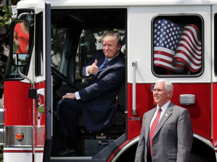 WASHINGTON, DC - JULY 17: U.S. President Donald Trump gives a thumbs up to journalists from inside a fire engine made by Pierce Manufacturing while touring a Made in America product showcase with Vice President Mike Pence on the South Lawn of the White House July 17, 2017 in Washington, DC. American manufacturers representing each of the 50 states participated in the showcase, including Bully Tools, Cheerwine, Stetson, Simms and RMA Armament, Charles Machine Works, Honckley Yachts, Altec Inc., Caterpiller, Pierce Manufacturing and others. (Photo by Chip Somodevilla/Getty Images)