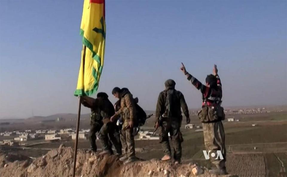 YPG fighters raise a flag as they reclaim Kobani on 26 January 2015 (VOA)