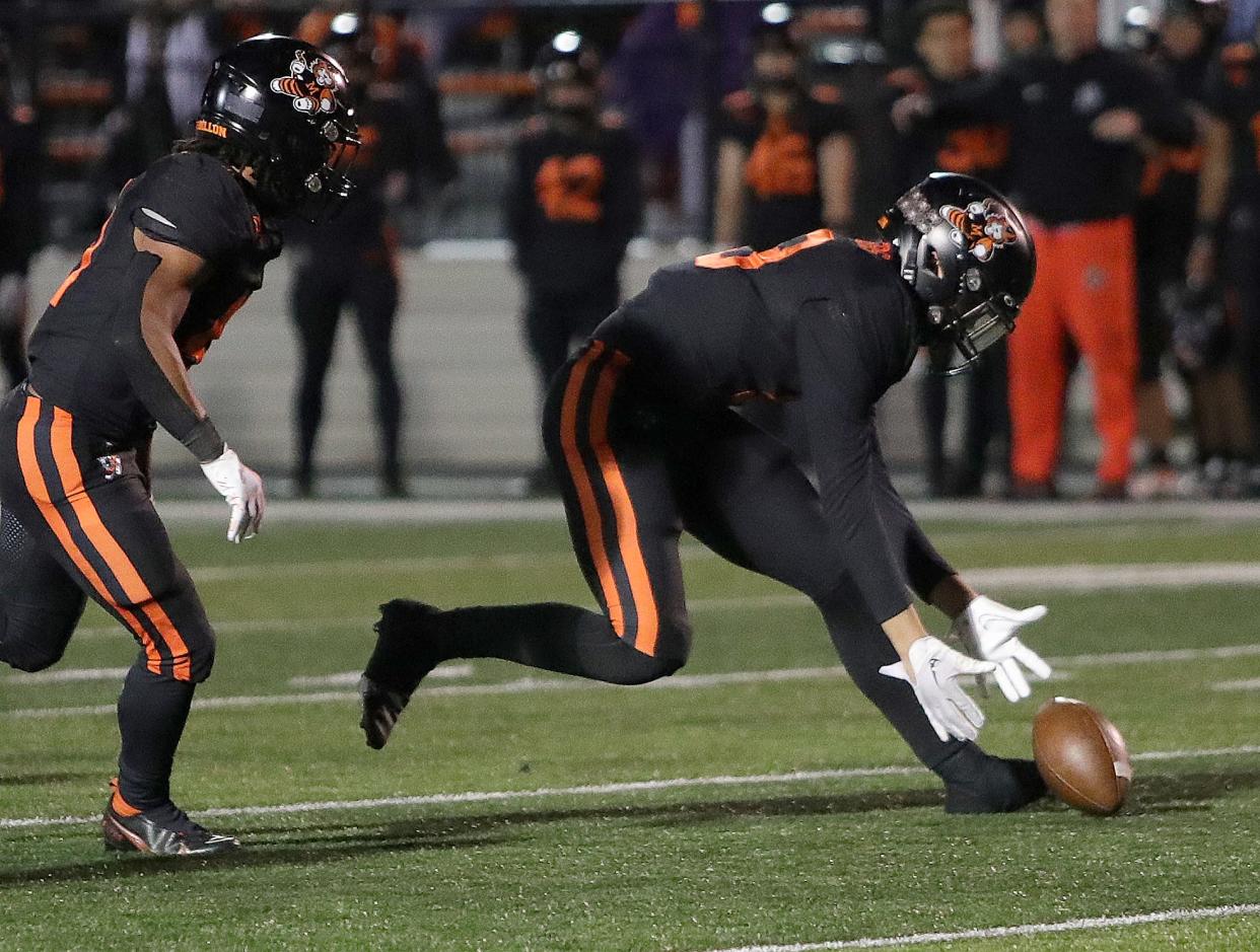 Massillon defender Vito McConnell, right, scoops up a fumbled and heads for a touchdown as teammate Ricardo Wells looks on during their playoff game against Westerville South, Friday, Nov. 3, 2023.