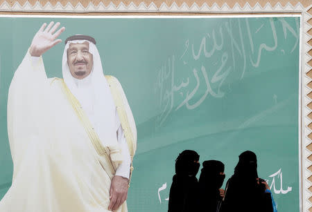 FILE PHOTO: Women walk past a poster of Saudi Arabia's King Salman bin Abdulaziz Al Saud during Janadriyah Cultural Festival on the outskirts of Riyadh, Saudi Arabia February 12, 2018. Picture taken February 12, 2018. REUTERS/Faisal Al Nasser/File Photo