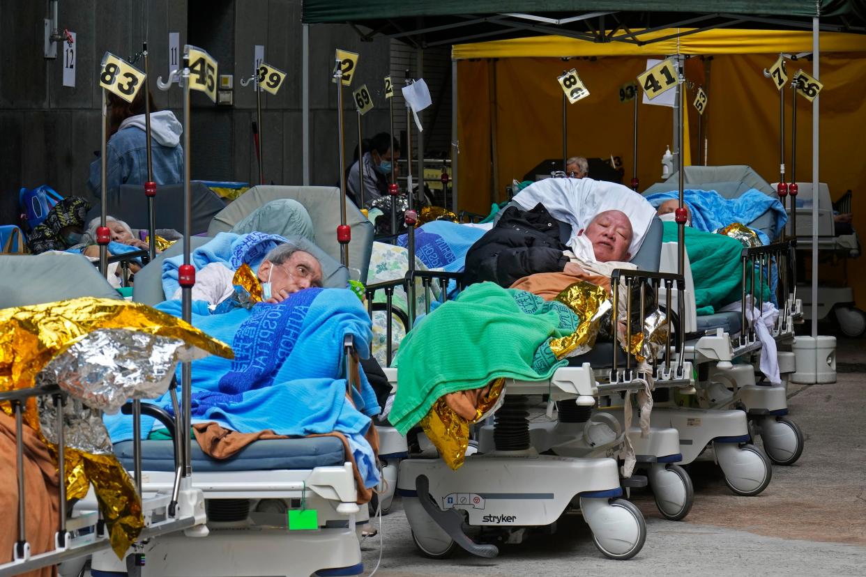 Patients lie on hospital beds waiting at a temporary holding area outside the Caritas Medical Centre in Hong Kong Wednesday, Feb. 16, 2022.