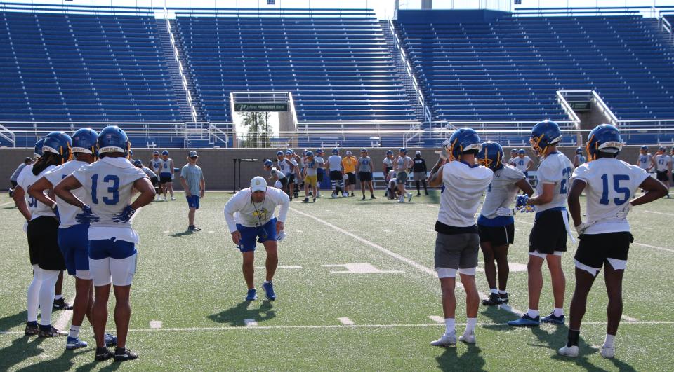 Cornerbacks coach Rob Erickson demonstrates a backpedaling drill for his players at a recent practice at Dana J. Dykhouse Stadium.