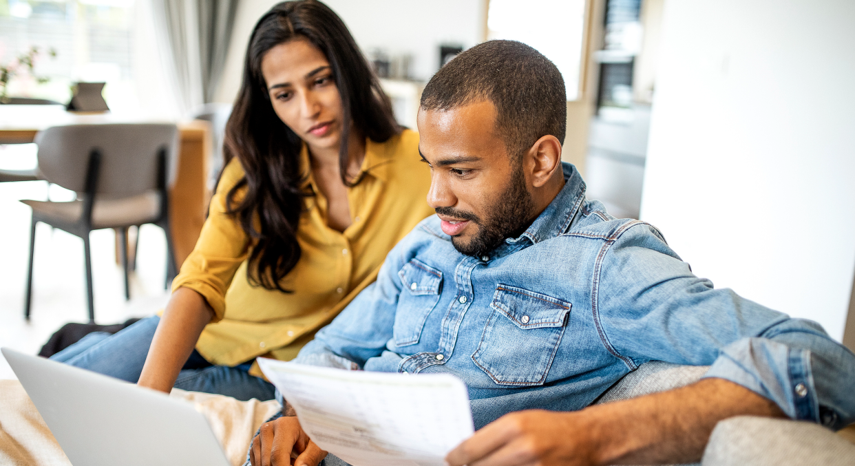 Couple in a relationship looking over bills in front of a laptop