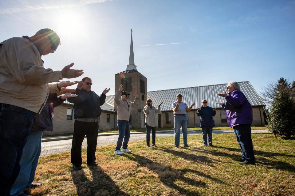 The Rev. Lou Ann Jones, right, leads prayer as eight people spread out around the flagpole at St. John's Blymire's United Church Of Christ near Dallastown, Pa., on March 16. They prayed for the community, nurses and doctors, government leaders and many others during the turmoil from the coronavirus pandemic.