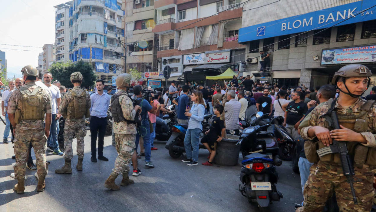 Lebanese security forces are deployed as people gather outside the Blom Bank branch in the capital Beirut's Tariq al-Jdideh neighbourhood on September 16, 2022, to express their support to a depositor, who stormed the bank demanding to withdraw his frozen savings. - Lebanon has been mired in an economic crisis for more than two years, since the value of its currency began plummeting and banks started imposing draconian restrictions on withdrawals. The holdup of a Beirut bank on Wednesday by an activist who filmed herself using a toy gun appears to have sparked a series of copycat raids by people fed up at being unable to withdraw their savings. There were at least another three such incidents in the country on Friday. (Photo by Ibrahim AMRO / AFP)