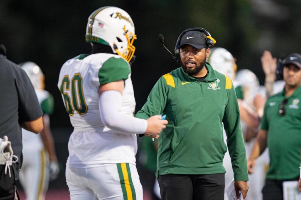 Rio Americano football head coach Reid Sanders talks to Rio Americano Raiders center Sam Enochian (60) after a play in the first half of the high school football game at Del Campo High School on Friday.