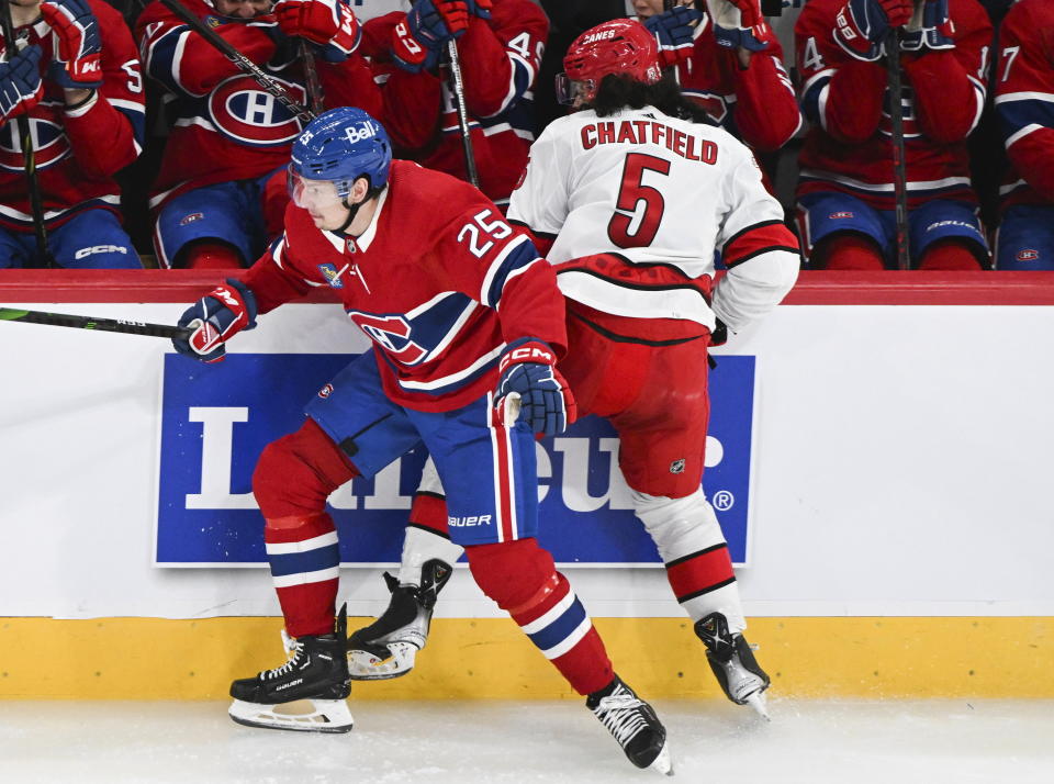 Montreal Canadiens' Denis Gurianov (25) checks Carolina Hurricanes' Jalen Chatfield (5) into the boards during the second period of an NHL hockey game Tuesday, March 7, 2023, in Montreal. (Graham Hughes/The Canadian Press via AP)