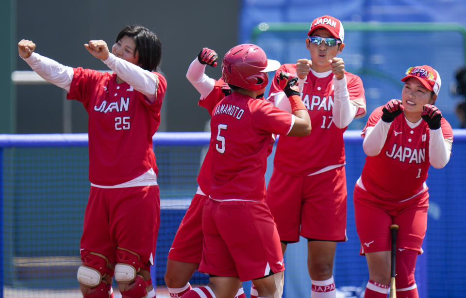 Japan's Yu Yamamoto celebrates with teammates after scoring a run during the softball game between Japan and Australia at the 2020 Summer Olympics, Wednesday, July 21, 2021, in Fukushima , Japan. (AP Photo/Jae C. Hong)