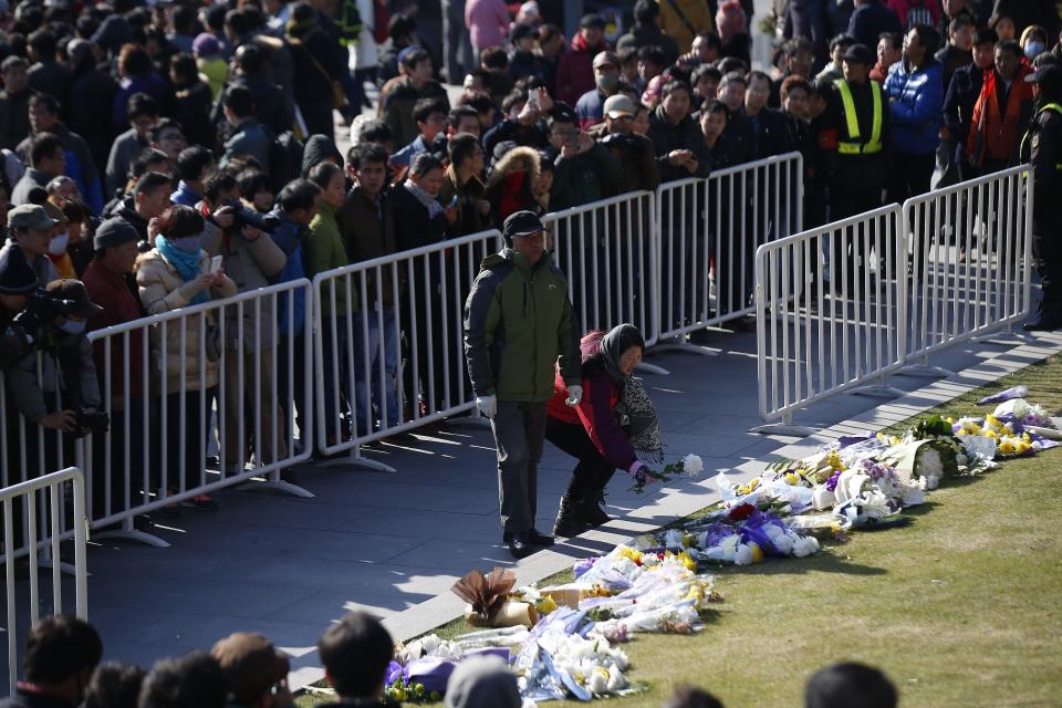 People lay down flowers during a memorial ceremony in memory of people who were killed in a stampede incident during a New Year's celebration on the Bund, in Shanghai