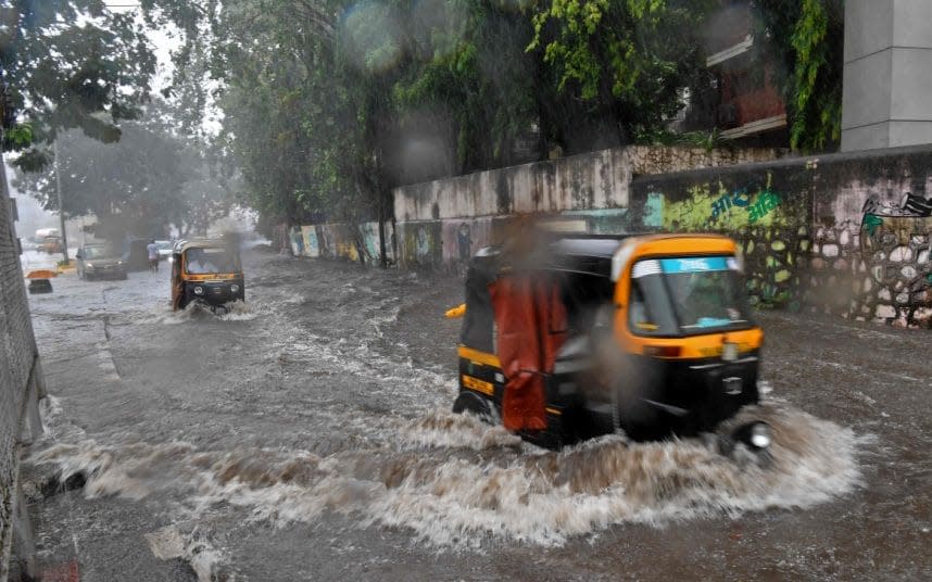 Rickshaws wade through a flooded street in Mumbai - INDRANIL MUKHERJEE/AFP  