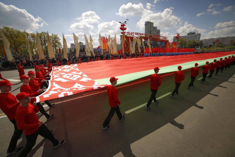 Belarusian sportsmen carry a state flag during the Victory Day military parade that marked the 75th anniversary of the allied victory over Nazi Germany, in Minsk, Belarus, Saturday, May 9, 2020. Belarus remains one of the few countries that hadn't imposed a lockdown or restricted public events despite recommendations of the World Health Organization. (AP Photo/Sergei Grits)