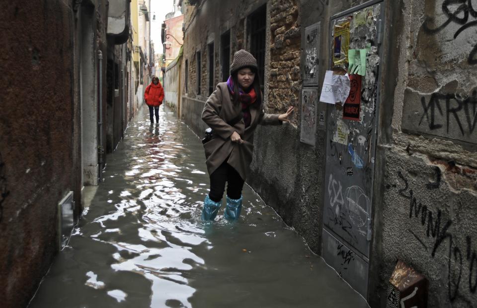 Women wade through water in Venice, Wednesday, Nov. 13, 2019. The high-water mark hit 187 centimeters (74 inches) late Tuesday, Nov. 12, 2019, meaning more than 85% of the city was flooded. The highest level ever recorded was 194 centimeters (76 inches) during infamous flooding in 1966. (AP Photo/Luca Bruno)