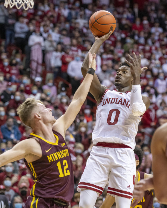 Indiana guard Xavier Johnson (0) puts up a shot over the defense of Minnesota guard Luke Loewe (12) during the second half of an NCAA college basketball game, Sunday, Jan. 9, 2022, in Bloomington, Ind. (AP Photo/Doug McSchooler)