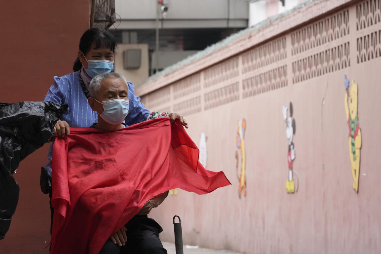 A barber prepares to cut the hair for a customer on a street, Monday, June 13, 2022, in Beijing. (AP Photo/Ng Han Guan)