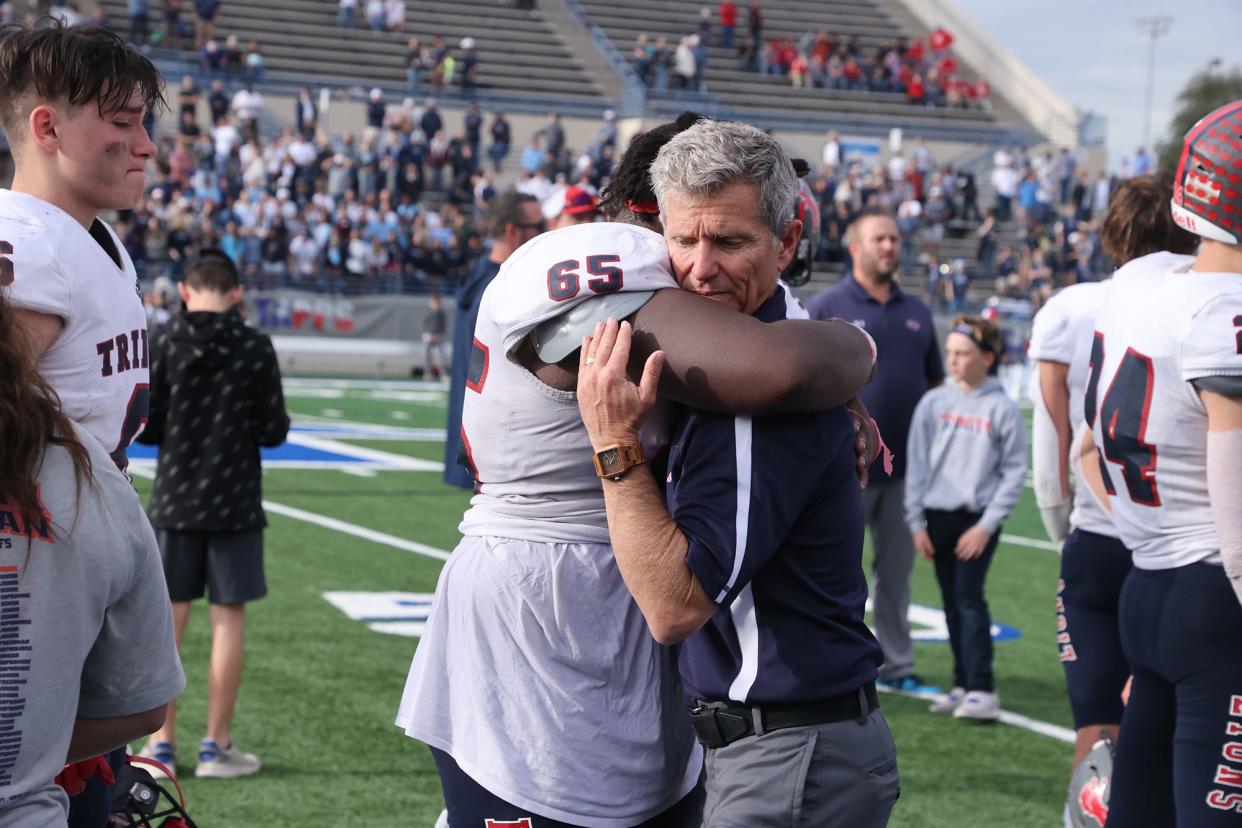 Trinity Christian head coach Kevin Spiller gives Jeremiah Isaac (65) a hug following a 16-7 loss to Cypress Christian in a TAPPS Division II state championship game at Waco ISD Stadium in Waco, Texas.