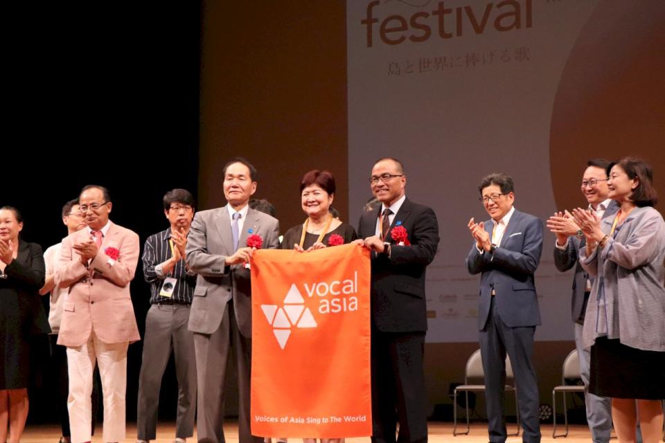 2020 Vocal Asia Festival將於台灣高雄市舉行，高雄市副市長葉匡石(右)特別出席11日晚間在日本香川縣高松市舉行的VAF閉幕儀式，並親自從香川縣知事濱田惠造(左)手中接下2020 VAF主辦會旗。圖中為VAF創辦人陳鳳文。(Vocal Asia提供)