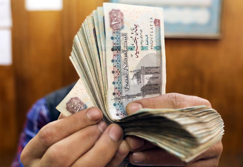 FILE PHOTO: An employee counts Egyptian pounds at a foreign exchange office in central Cairo