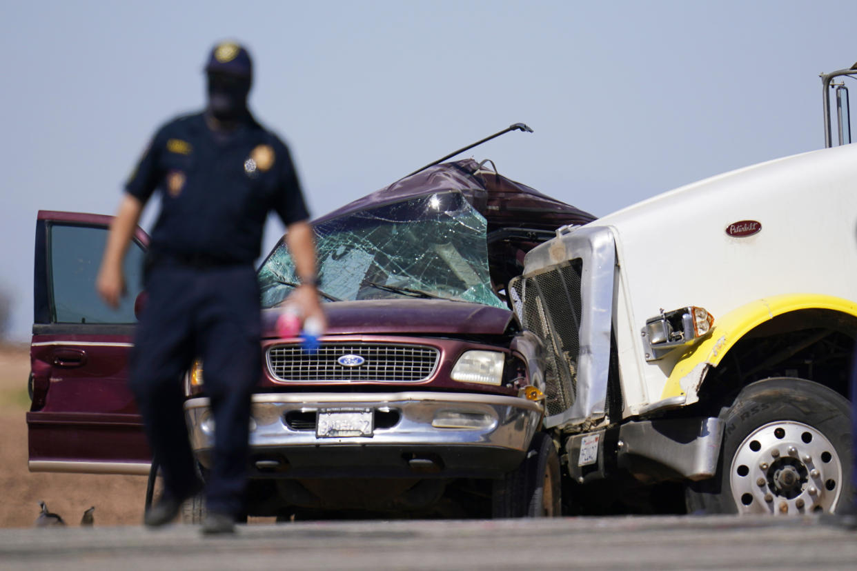 Law enforcement officers work at the scene of a deadly crash in Holtville, Calif., on Tuesday, March 2, 2021. Authorities say a semi-truck crashed into an SUV carrying multiple people on a Southern California highway, killing at least 13 people and injuring others. (AP Photo/Gregory Bull)