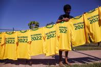 A boy hangs up t-shirts with the name of Brazilian President Jair Bolsonaro in the neighborhood of Estrutural in Brasilia