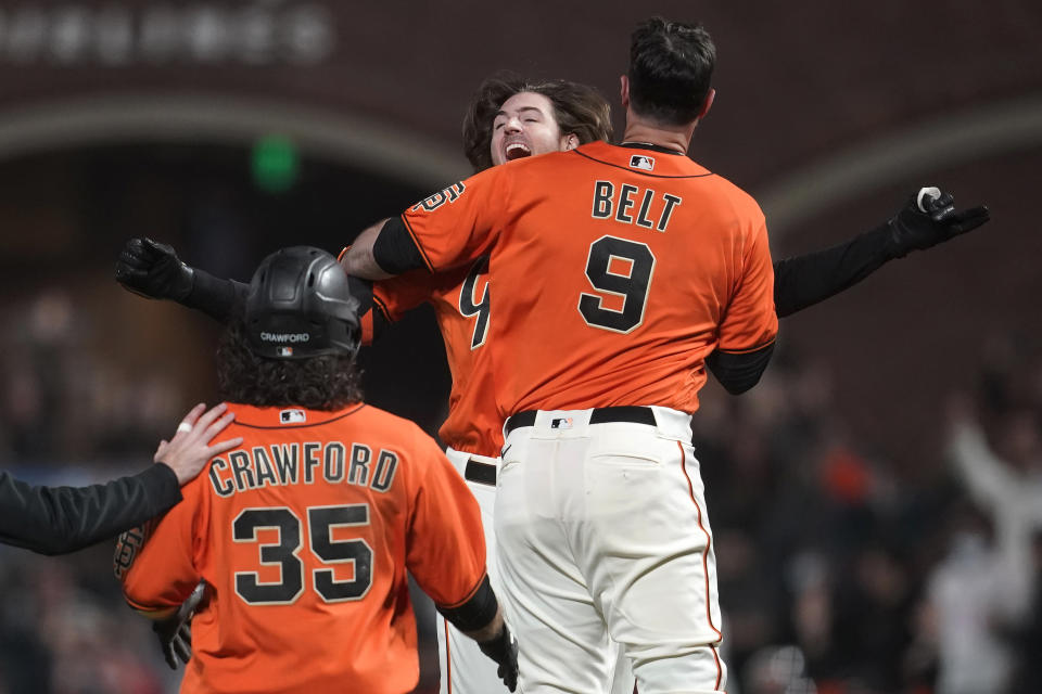 San Francisco Giants' Kevin Gausman, rear, celebrates with Brandon Belt (9) after hitting a sacrifice fly that scored Brandon Crawford (35) during the 11th inning of the team's baseball game against the Atlanta Braves in San Francisco, Friday, Sept. 17, 2021. (AP Photo/Jeff Chiu)