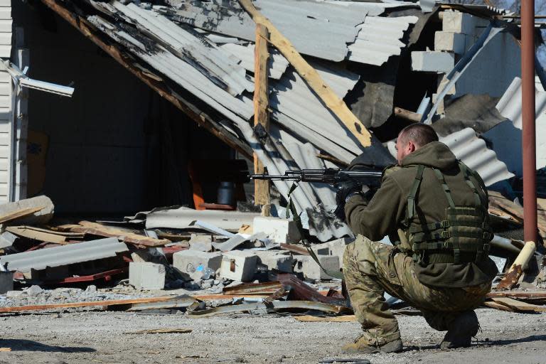 A soldier of the self-proclaimed Donetsk People's Republic secures a street in front of a recently damaged building in Shyrokyne, near Mariupol, on March 20, 2015