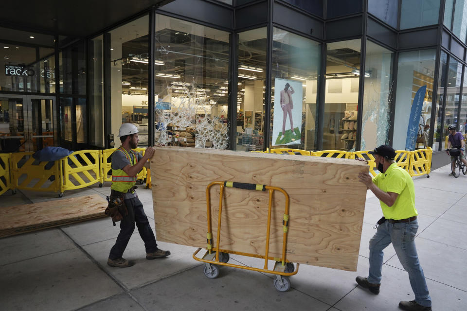 Crews worked to board up the broken windows at the Nordstrom Rack on Nicollet Mall, Thursday, Aug. 27, 2020, in Minneapolis, where several businesses were damaged by a group of looters Wednesday night after the suicide of a homicide suspect on the Mall ignited rioting. (Anthony Souffle/Star Tribune via AP)