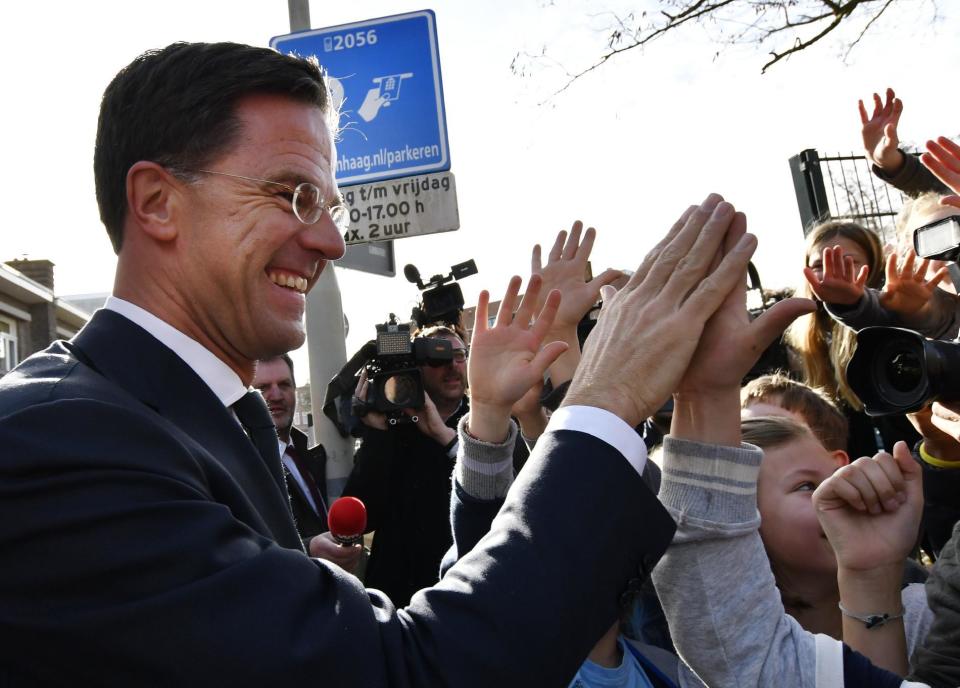 Dutch Prime Minister Mark Rutte gives 'high five' to children after casting his vote for the Dutch general election in The Hague, Netherlands, Wednesday, March 15, 2017. (AP Photo/Patrick Post)
