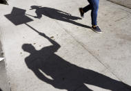 Shadows of striking actors including SAG-AFTRA member Isaac Burks, left, are pictured tapping together their picket signs outside Netflix studios, Wednesday, Nov. 8, 2023, in Los Angeles. (AP Photo/Chris Pizzello)