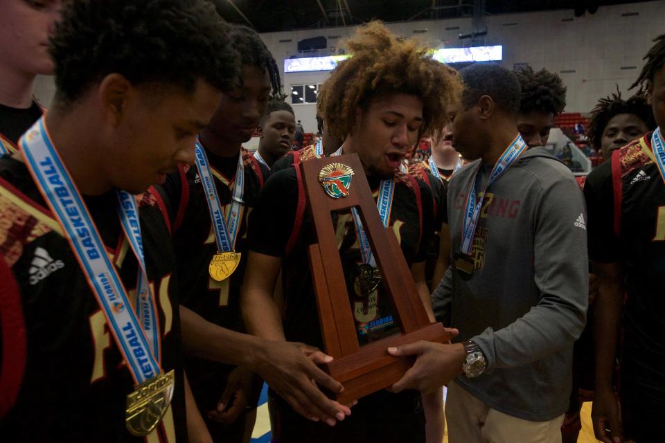 Florida High senior guard Tre Donaldson (3) accepts the state championship trophy from head coach Charlie Ward following the Seminoles state championship win over Riviera Prep on March 4, 2022, at R.P. Funding Center in Lakeland.