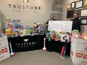 Justin Hebner, Mortgage Closing Specialist and Steve Steen, Chief Business Officer, pose with a check for $3,000 and some of the nearly 1,800 toys collected during the holiday toy drive at the Corporate Center in Plymouth, Minnesota.