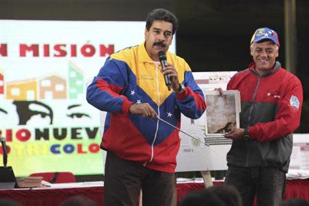 Venezuela's President Nicolas Maduro (L) shows a picture of a metro tunnel wall with an image which he says is the face of late President Hugo Chavez, in Caracas October 30, 2013. REUTERS/Miraflores Palace/Handout via Reuters