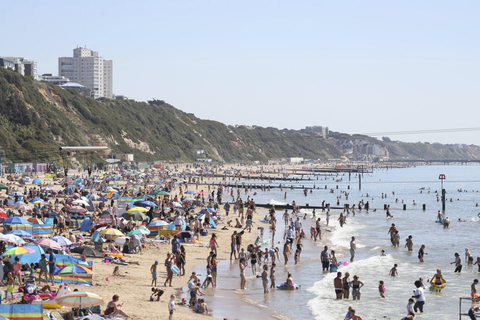 People gather on the beach at Bournemouth, Southern England, Friday Aug. 7, 2020. The UK could see record-breaking temperatures with forecasters predicting Friday could be the hottest day of the year. (Andrew Matthews/PA via AP)