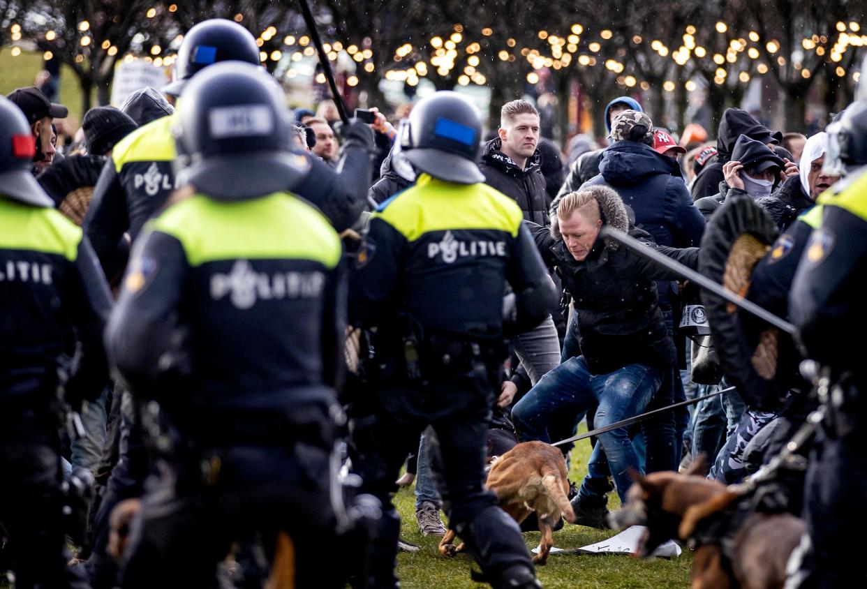 <p>Demonstrators face Dutch police at the Museumplein, in Amsterdam, on January 17, 2021</p> (Photo by ROBIN VAN LONKHUIJSEN/ANP/AFP via Getty Images)
