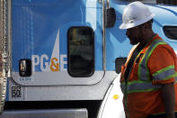 FILE - In this Aug. 15, 2019, file photo, a Pacific Gas & Electric worker walks in front of a truck in San Francisco. Pacific Gas & Electric and a group of insurers say they have reached an $11 billion settlement to cover most of the claims from the 2017 and 2018 wildfires in California. The utility said in a statement Friday, Sept. 13, that the tentative agreement covers 85% of the insurance claims, including a fire that decimated the town of Paradise. (AP Photo/Jeff Chiu, File)